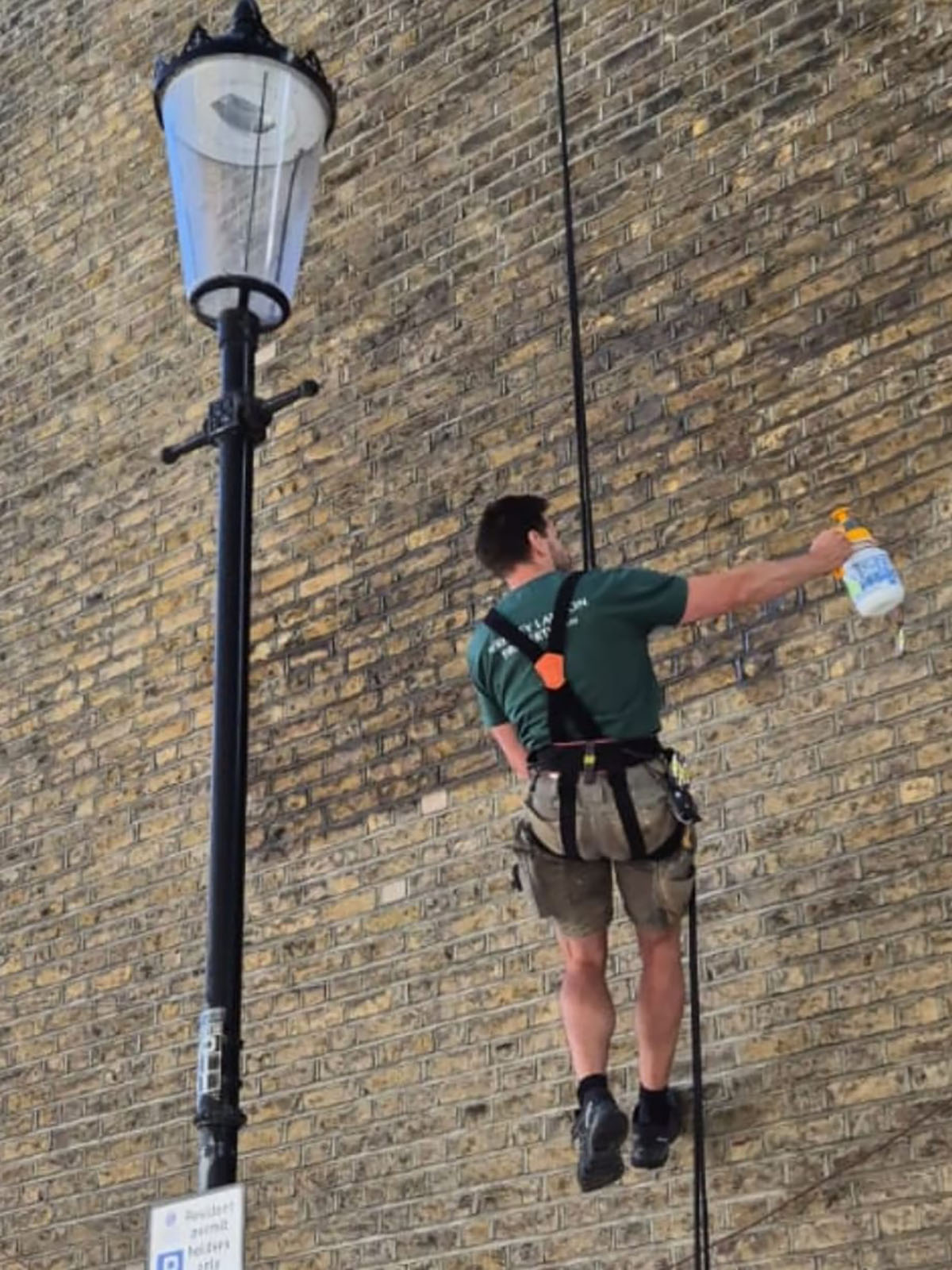 Henry using rope access spraying exterior wall