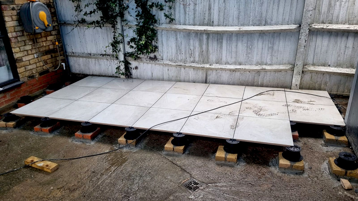 View of the thick Enis Ivory outdoor tiles being laid onto the adjustable pedestal PETG stands and set in place.
