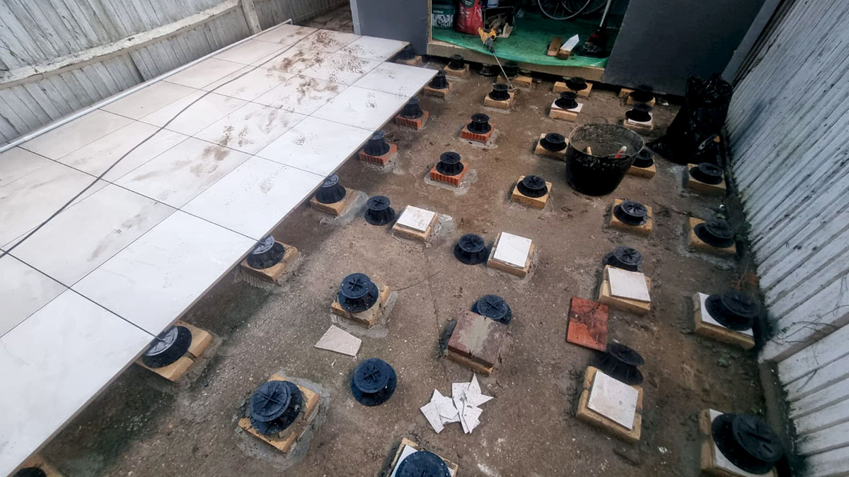 View of the thick Enis Ivory outdoor tiles being laid onto the adjustable pedestal PETG stands and set in place.